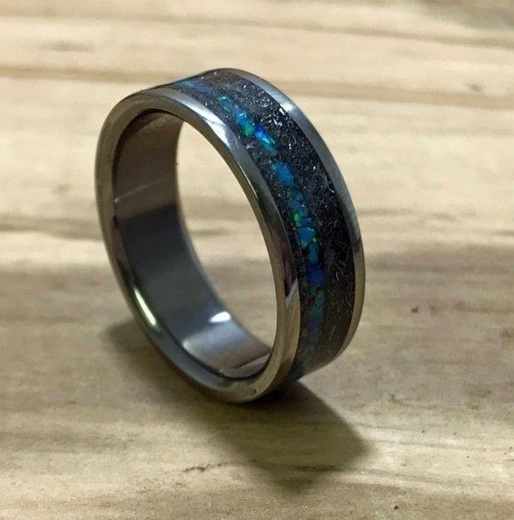 The Blue Opal Titanium Meteorite Wedding Band is a stunning and unique choice for couples seeking a one-of-a-kind symbol of their love. This exquisite piece of jewelry combines the beauty of blue opal, the strength of titanium, and the rarity of a meteorite, creating a truly special and meaningful wedding band. With its captivating colors and celestial origins, this ring is sure to be a conversation starter and a cherished heirloom for years to come.