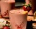 A head-on shot in direct sunlight shows a strawberry lemonade smoothie garnished with a whole strawberry and a little lemon slice.