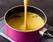 Easy vegan cheese sauce in a pink pan with a whisk.