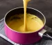 Easy vegan cheese sauce in a pink pan with a whisk.