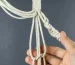 Macrame cord being knotted to make macrame plant hanger.