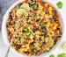 Overhead view on a large bowl of Brown rice and Quinoa Salad loaded with mango and vegetables.